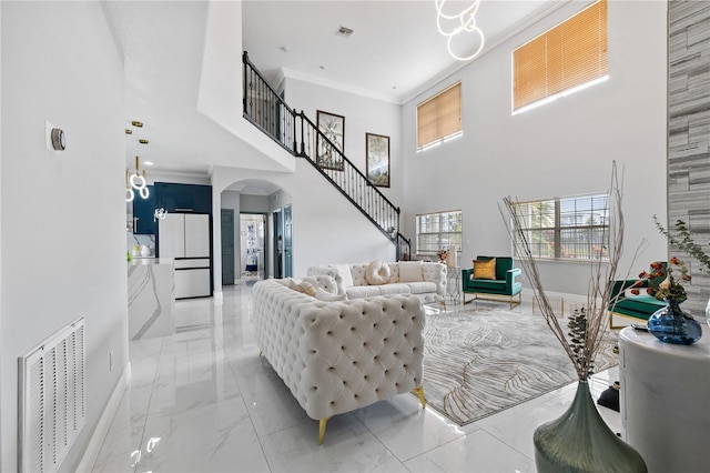 living room with a high ceiling, crown molding, and a chandelier