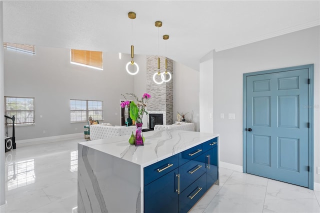 kitchen featuring hanging light fixtures, light stone countertops, blue cabinetry, a fireplace, and a center island