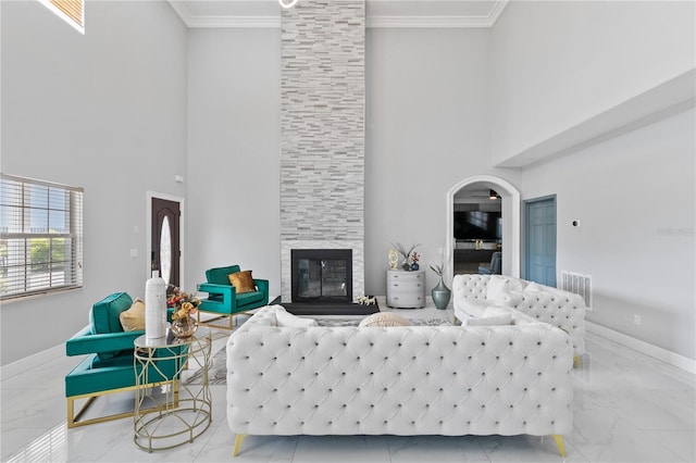 living room featuring ornamental molding, a fireplace, and a towering ceiling