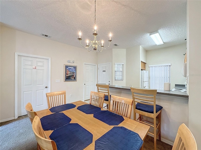 dining area featuring hardwood / wood-style floors, a textured ceiling, and an inviting chandelier