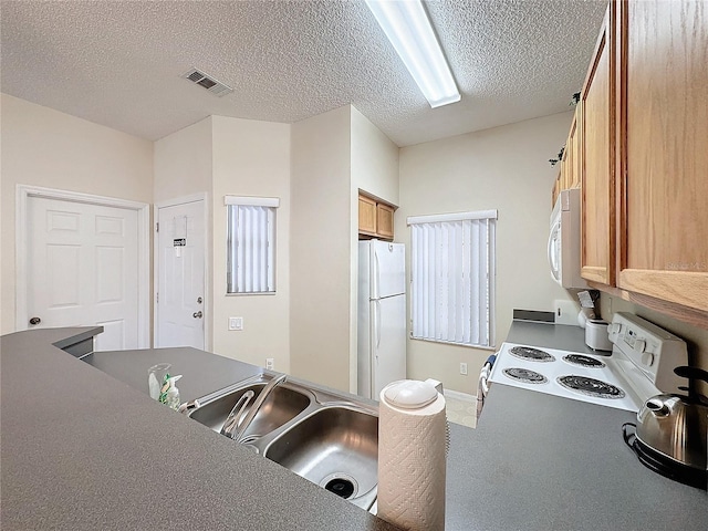 kitchen featuring a textured ceiling, sink, and white appliances