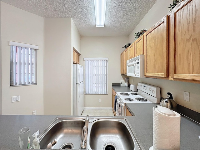 kitchen featuring a textured ceiling, sink, and white appliances