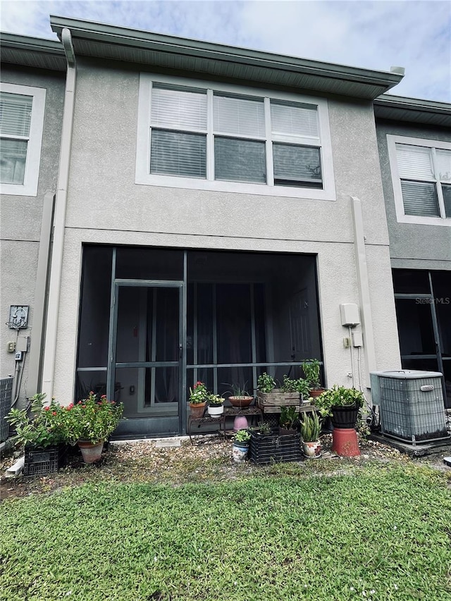 rear view of house featuring a yard, a sunroom, and central AC unit