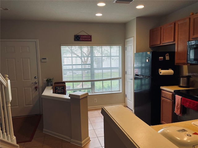 10453 Westpark Preserve Blvd, Tampa, FL 33625 - kitchen with black appliances, light tile patterned flooring, light countertops, brown cabinets, and a peninsula