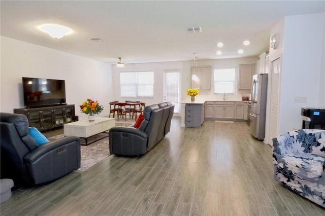 living room featuring sink, light wood-type flooring, and ceiling fan