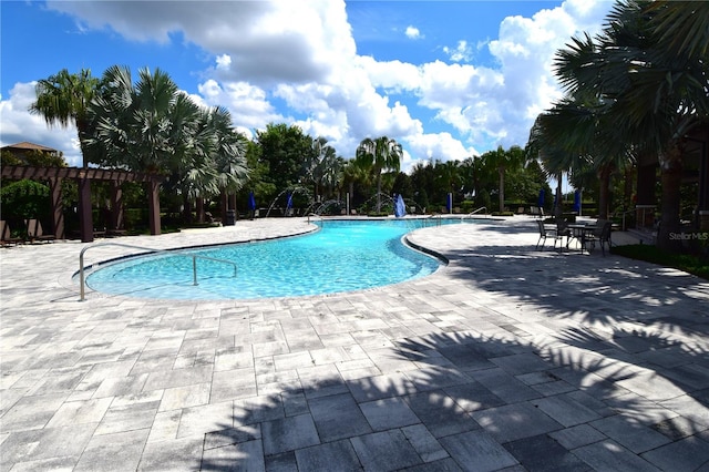 view of pool featuring pool water feature, a patio, and a pergola