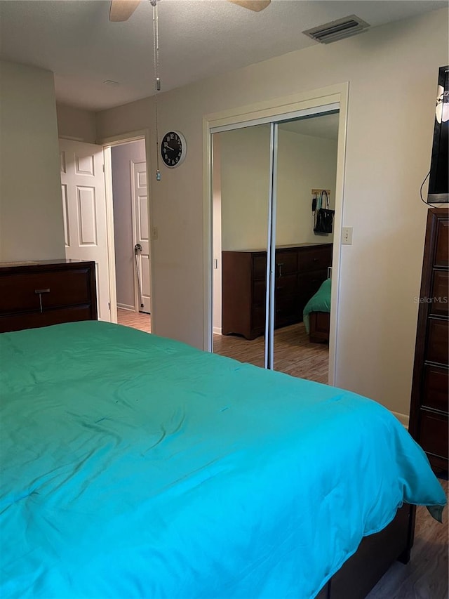 bedroom with hardwood / wood-style flooring, ceiling fan, and a closet