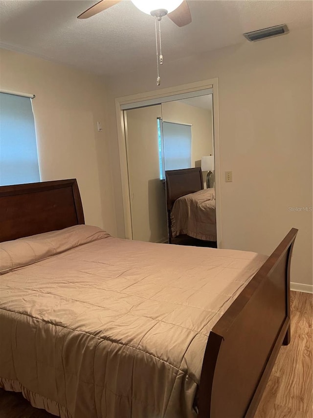 bedroom with a closet, light wood-type flooring, and ceiling fan