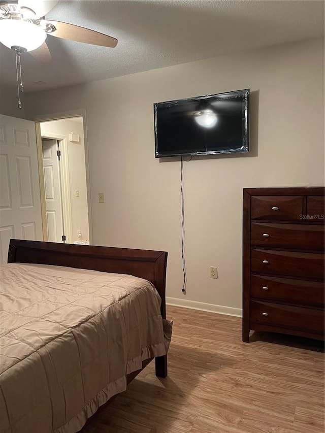 bedroom featuring ceiling fan, a textured ceiling, and light hardwood / wood-style floors