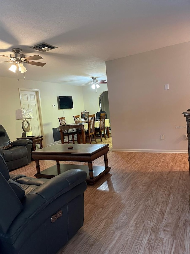 living room with ceiling fan, wood-type flooring, and a textured ceiling