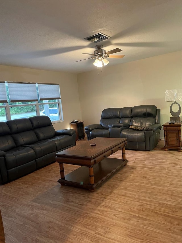 living room featuring wood-type flooring, a textured ceiling, and ceiling fan