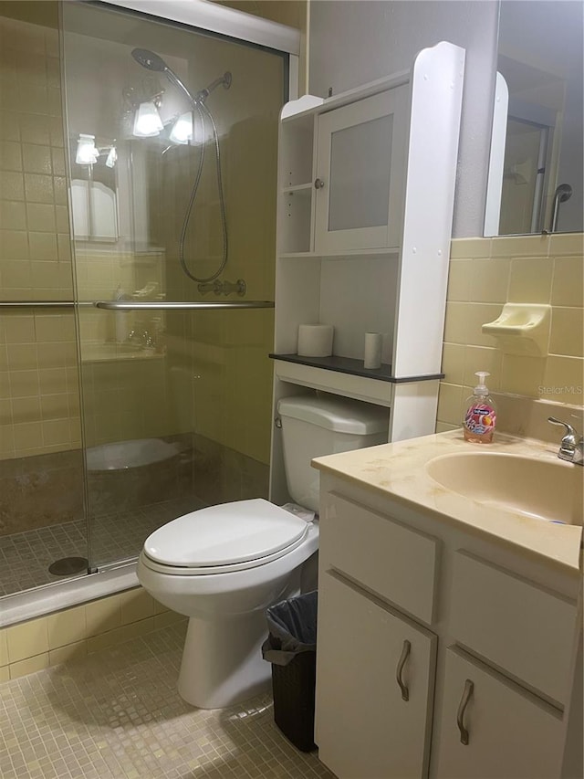 bathroom featuring tile patterned flooring, toilet, tasteful backsplash, a shower with door, and vanity