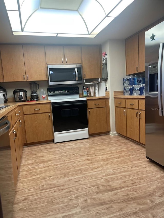 kitchen with appliances with stainless steel finishes and light hardwood / wood-style flooring