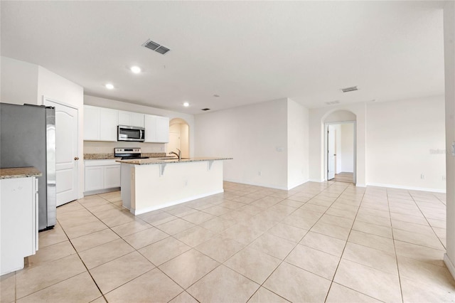 kitchen featuring light stone counters, white cabinets, sink, a center island with sink, and stainless steel appliances