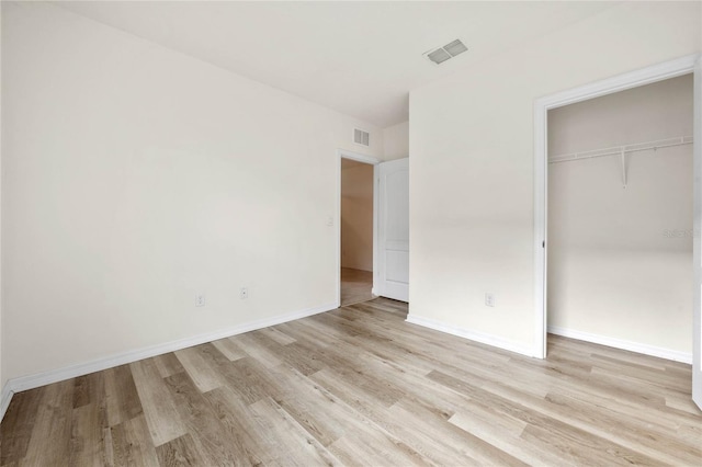 unfurnished bedroom with light wood-type flooring and a closet