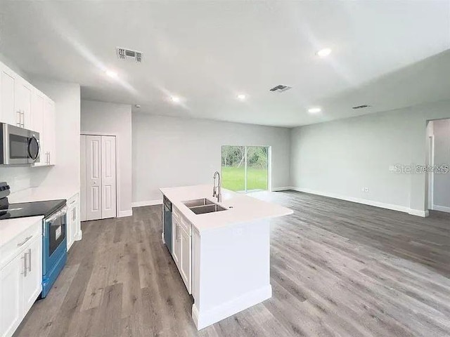 kitchen with an island with sink, sink, dark wood-type flooring, white cabinetry, and stainless steel appliances