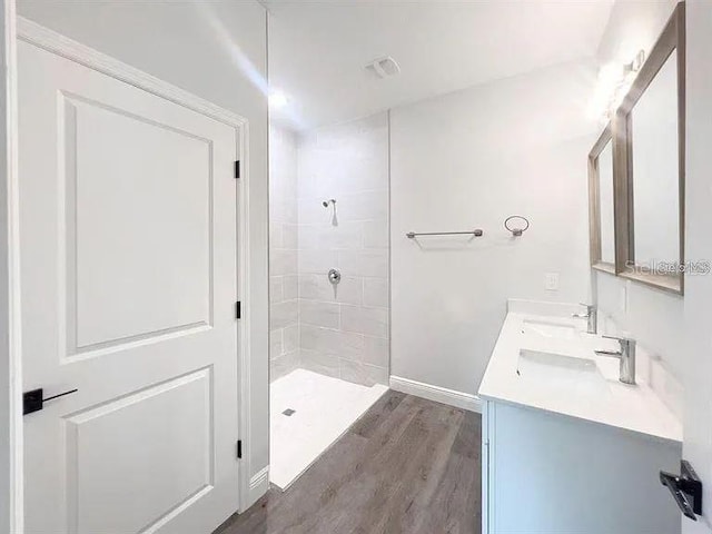 bathroom with a tile shower, hardwood / wood-style floors, and vanity