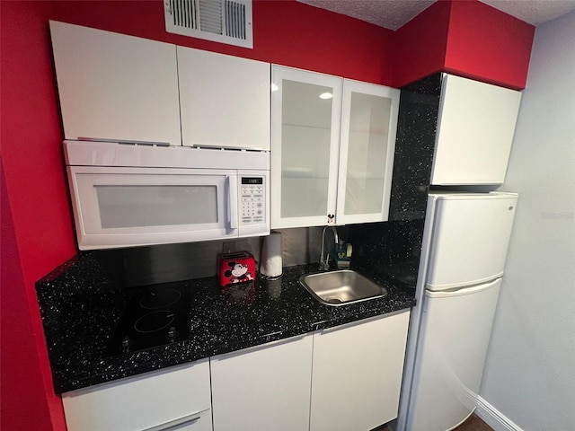 kitchen featuring white appliances, sink, backsplash, white cabinets, and a textured ceiling