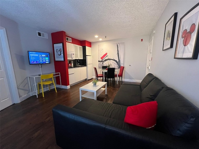 living room with a textured ceiling and dark hardwood / wood-style floors