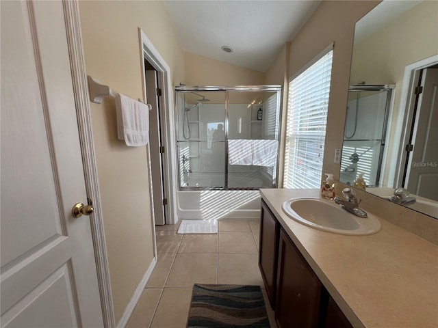 bathroom featuring tile patterned flooring, vaulted ceiling, a shower with shower door, and vanity