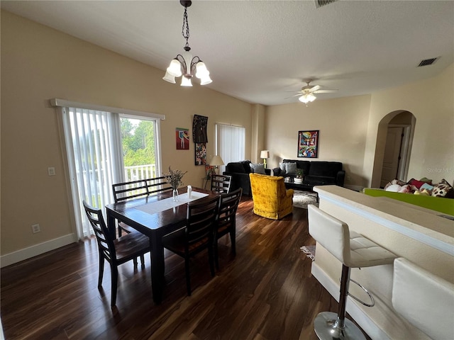 dining space with a textured ceiling, ceiling fan with notable chandelier, and dark hardwood / wood-style floors