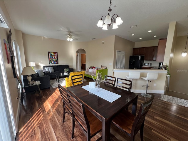 dining room featuring ceiling fan with notable chandelier and dark wood-type flooring