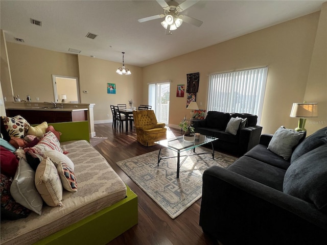 living room with ceiling fan with notable chandelier and dark hardwood / wood-style flooring