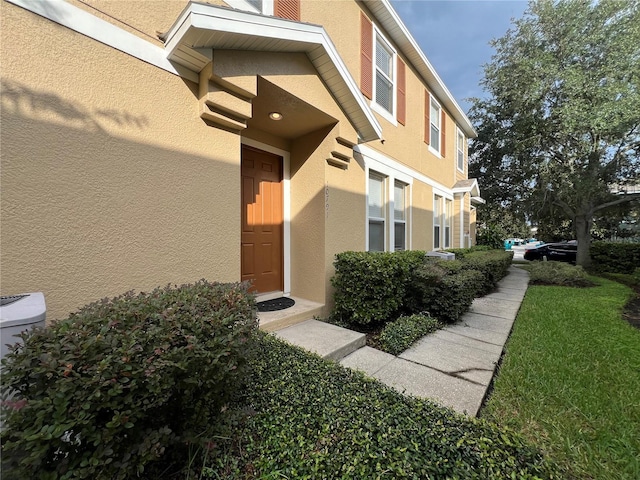 view of exterior entry featuring a lawn