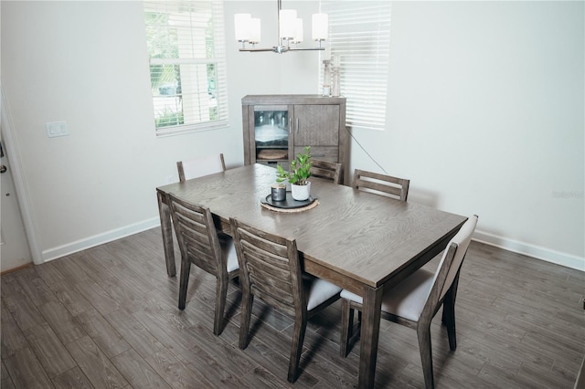 dining space featuring dark wood-type flooring and a notable chandelier