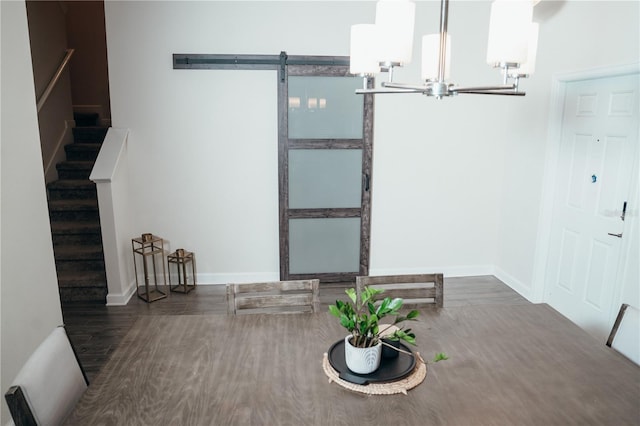 unfurnished dining area with a chandelier, a barn door, and dark wood-type flooring