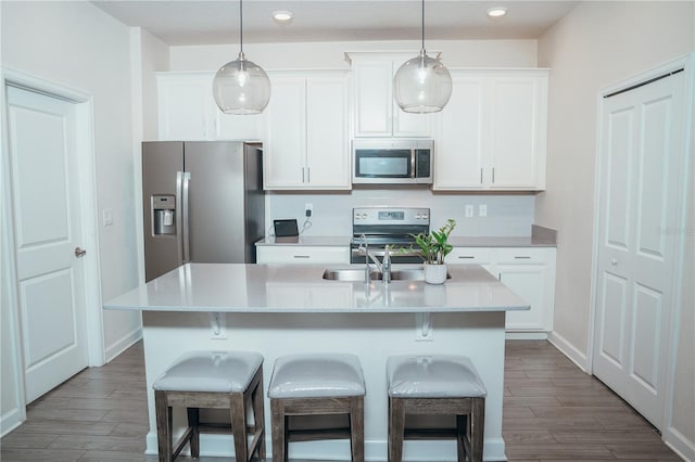 kitchen featuring a center island with sink, stainless steel appliances, and hanging light fixtures