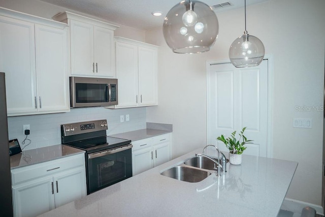 kitchen featuring appliances with stainless steel finishes, tasteful backsplash, sink, decorative light fixtures, and white cabinets