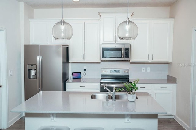 kitchen featuring white cabinetry, decorative backsplash, a center island with sink, and appliances with stainless steel finishes