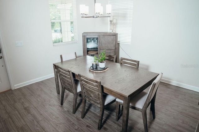 dining area featuring dark wood-type flooring and an inviting chandelier