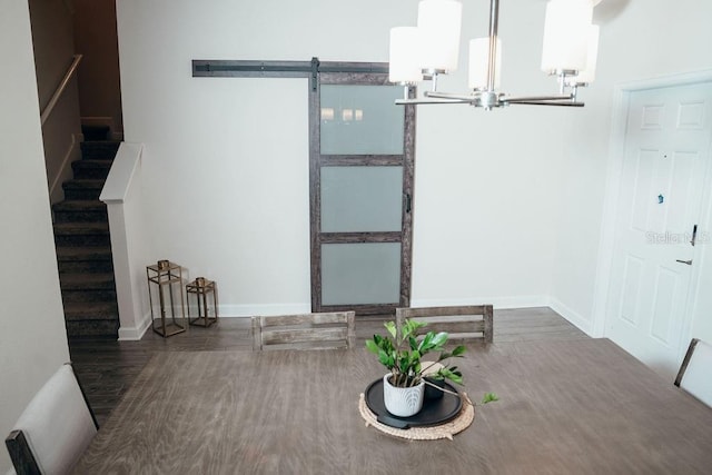 unfurnished dining area with a barn door, dark wood-type flooring, and a notable chandelier