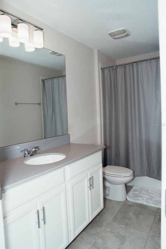 bathroom featuring a textured ceiling, vanity, and toilet