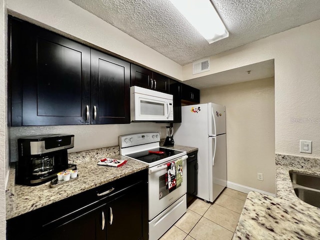 2210 Grand Cayman Ct Unit 1722, Kissimmee, FL 34741 - kitchen featuring white appliances, dark cabinetry, a textured ceiling, and light tile patterned floors
