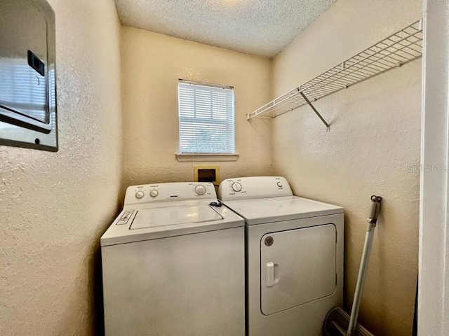 laundry area with washer and clothes dryer and a textured ceiling