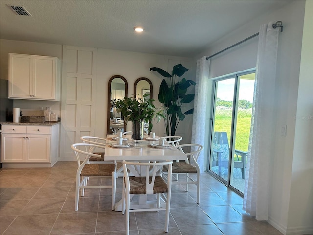 dining space featuring a textured ceiling and light tile patterned flooring