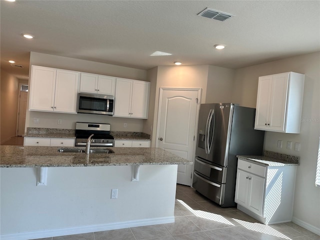 kitchen with a center island with sink, white cabinetry, and stainless steel appliances