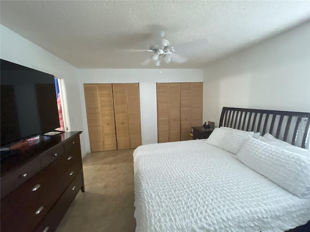 bedroom with carpet flooring, ceiling fan, a textured ceiling, and multiple closets