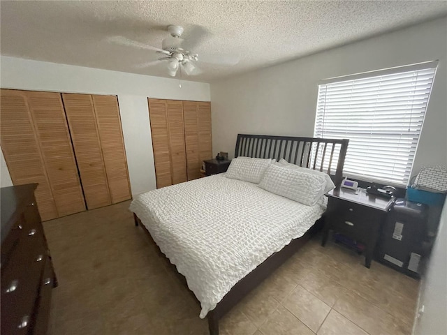 bedroom featuring multiple closets, ceiling fan, light tile patterned floors, and a textured ceiling