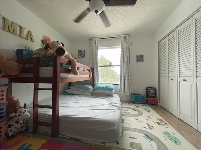 tiled bedroom with ceiling fan, a closet, and a textured ceiling