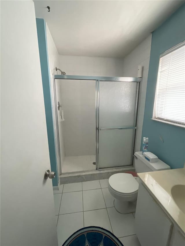 bathroom featuring tile patterned flooring, vanity, a shower with door, and toilet