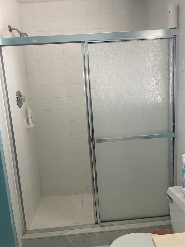 bathroom with toilet and a shower with shower door