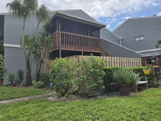 back of property with a lawn and a sunroom