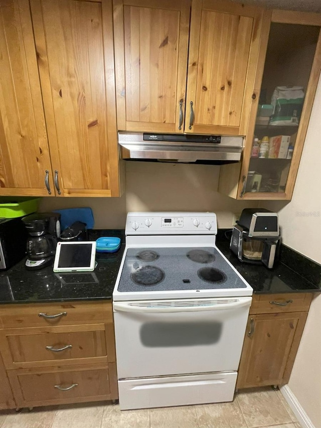 kitchen with electric range, light tile patterned floors, and dark stone counters