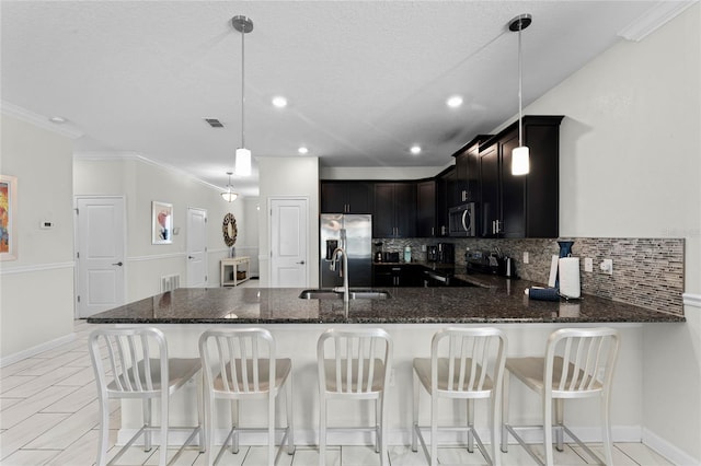 kitchen featuring stainless steel appliances, decorative light fixtures, sink, and a kitchen breakfast bar