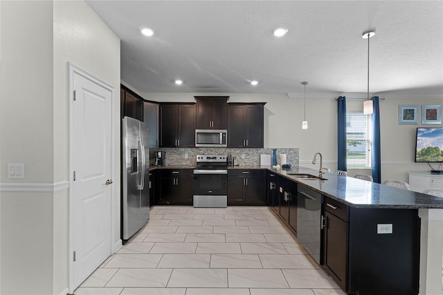 kitchen featuring sink, kitchen peninsula, decorative light fixtures, backsplash, and appliances with stainless steel finishes