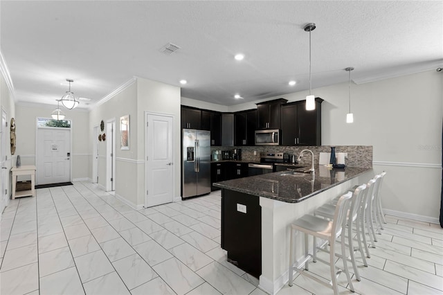 kitchen with pendant lighting, tasteful backsplash, sink, ornamental molding, and appliances with stainless steel finishes